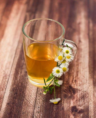 Chamomile tea on wooden background. Next to a cup of chamomileの写真素材