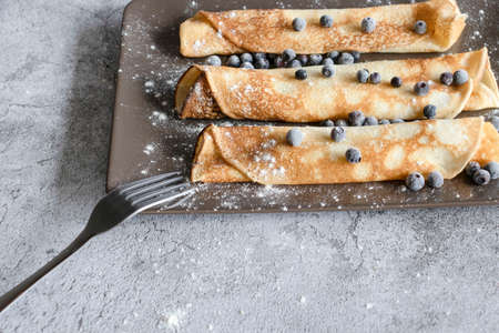 Homemade pancakes with blueberries. On gray plates and concrete background