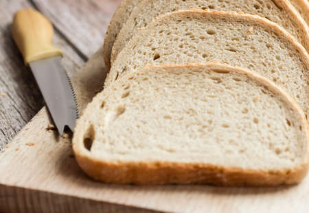 Sliced â€‹â€‹fresh bread and a cutting knife on a rustic table