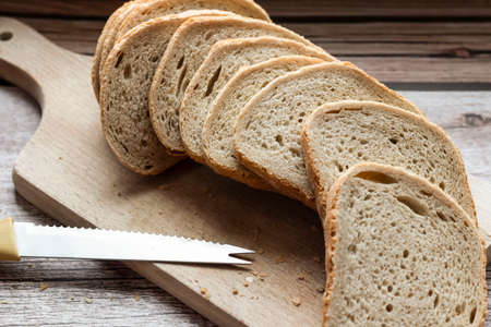 Sliced â€‹â€‹fresh bread and a cutting knife on a rustic table