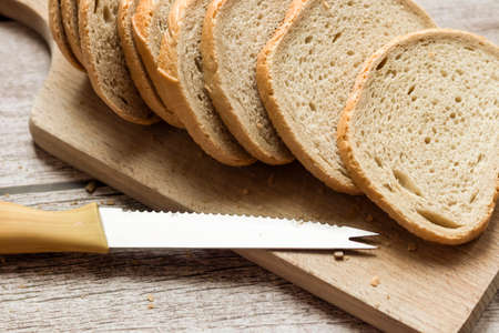 Sliced ââfresh bread and a cutting knife on a rustic tableの写真素材
