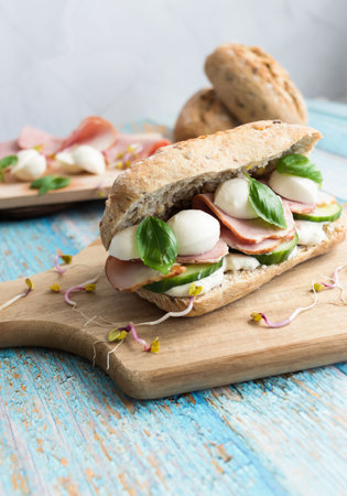 Sandwich with mozzarella, tomato and basil on wooden boardの写真素材