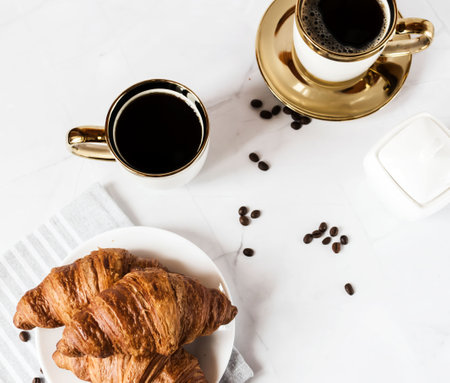 Breakfast with coffee and croissants on a white marble tableの写真素材