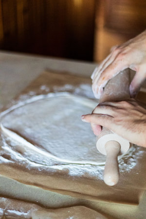 Hands kneading dough on a wooden table in a bakery