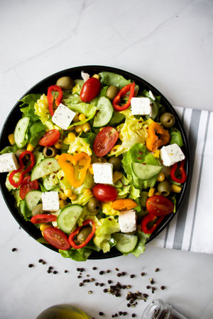 Greek salad with feta cheese and fresh vegetables on white marble backgroundの写真素材