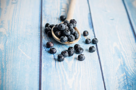 Fresh blueberries in a wooden spoon on a blue wooden background.の写真素材