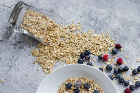Oatmeal with blueberries and raspberries in a glass jar on a concrete backgroundの写真素材
