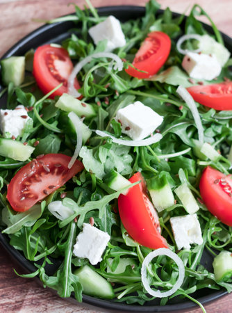 Fresh salad with arugula, feta cheese and tomatoes on plateの写真素材