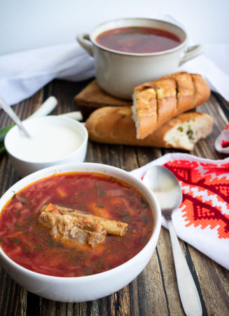 Traditional Russian borscht with sour cream and bread on a wooden table