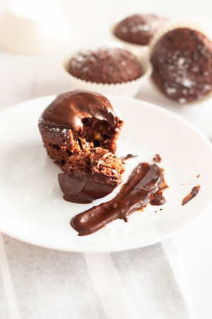 Chocolate muffins with chocolate icing on a white plate, selective focus.の写真素材