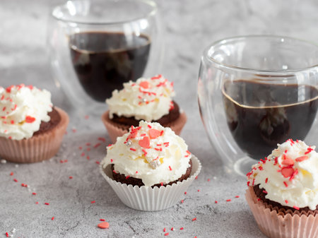Chocolate cupcakes with whipped cream and coffee on a gray background