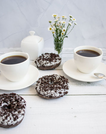 Cup of coffee and chocolate donuts on a white wooden tableの写真素材
