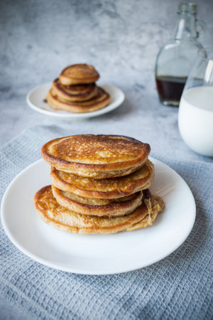 Pancakes with maple syrup on a white plate, selective focus