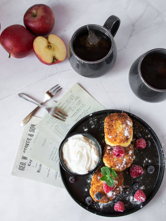 Cottage cheese pancakes with fresh raspberries, blackberries and blueberries served with a cup of black teaの写真素材
