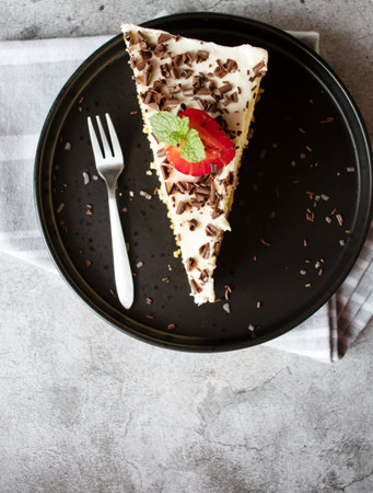 Piece of chocolate cake with whipped cream and strawberry on black plate
