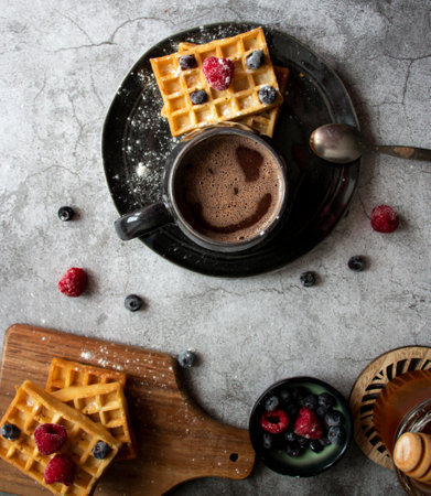 Cup of coffee with waffles and berries on a gray backgroundの写真素材