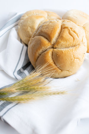 Bread and wheat ears on white tablecloth, close-up
