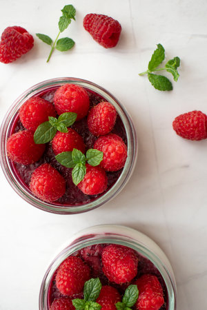 Raspberry dessert in a glass jar with fresh raspberries and mint.