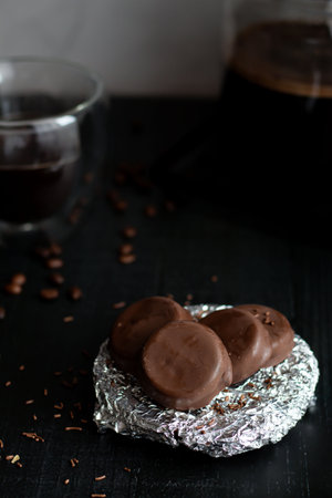 Chocolate candies with coffee beans on a black wooden background.の写真素材