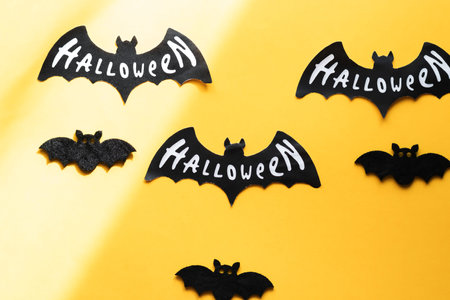 Halloween black paper bats on yellow background. Happy Halloween concept.