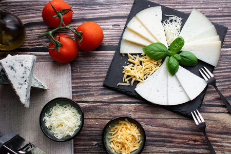 Cheese platter with tomatoes, mozzarella cheese and basil on wooden backgroundの写真素材
