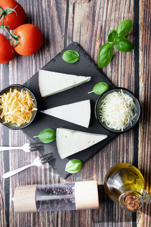 Piece of Parmesan cheese with basil and tomatoes on wooden background