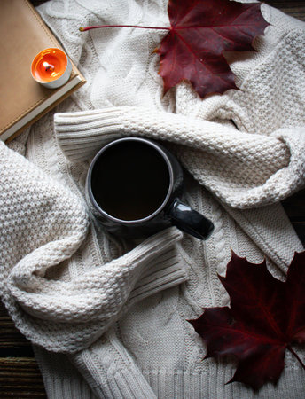Cup of hot drink, book and autumn leaves on wooden backgroundの写真素材