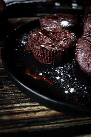 Chocolate muffins on a black plate on a wooden background. tinting. selective focusの写真素材