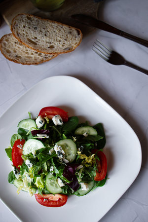 Fresh salad with tomatoes, cucumbers and blue cheese on white plateの写真素材