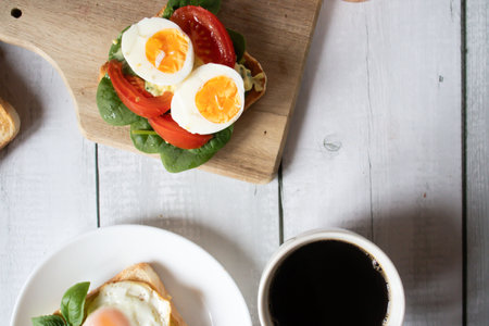 Sandwich with eggs, tomato and lettuce on a white wooden tableの写真素材