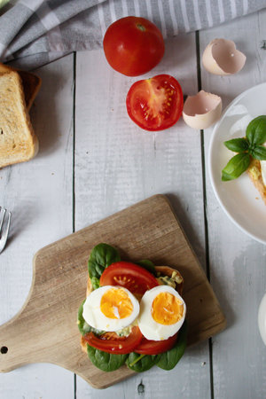 Sandwiches with egg, tomatoes and basil on a wooden board