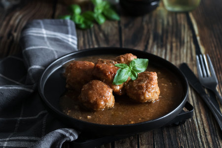 Meatballs with sauce in a frying pan on a dark wooden backgroundの写真素材