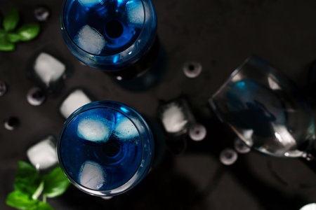 Blue cocktail with ice cubes and mint on black background, top viewの写真素材