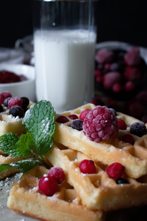 Belgian waffles with fresh berries and a glass of milk.