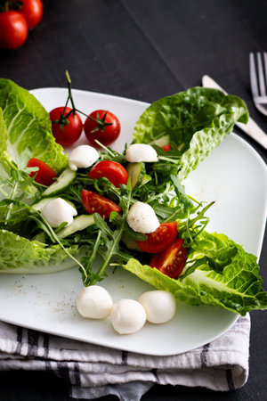 salad with mozzarella and cherry tomatoes on a black backgroundの写真素材