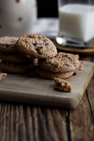 Chocolate chip cookies on wooden board and glass of milk on wooden tableの写真素材