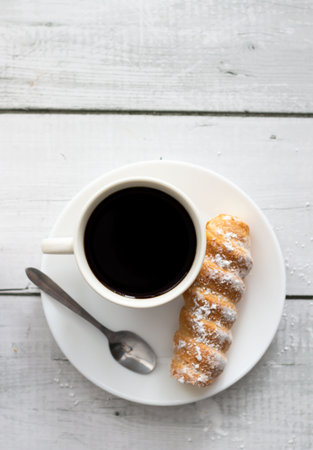 Cup of coffee and croissant on a white wooden background