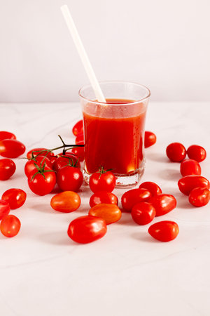 Tomato juice in a glass and fresh tomatoes on a white backgroundの写真素材