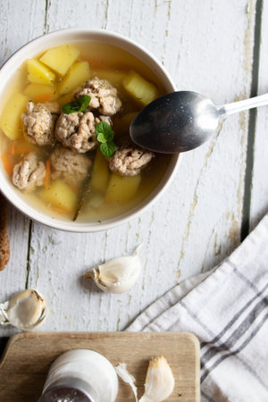 Vegetable soup with meatballs in a bowl on wooden background