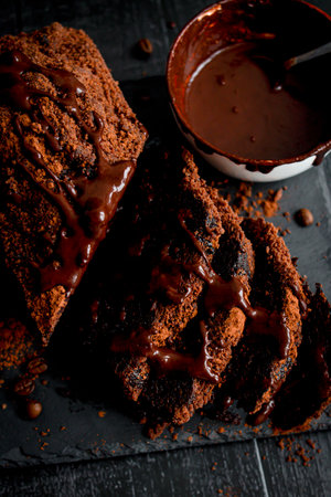 Chocolate brownies with chocolate glaze and cocoa powder on black background