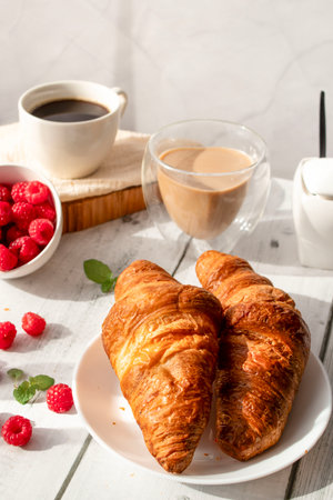 Fresh croissants with raspberries and coffee on white backgroundの写真素材