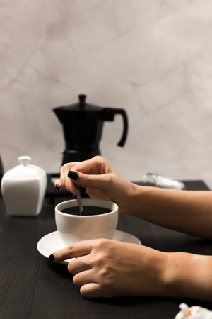 Female hands holding a cup of coffee in the kitchen, close-upの写真素材