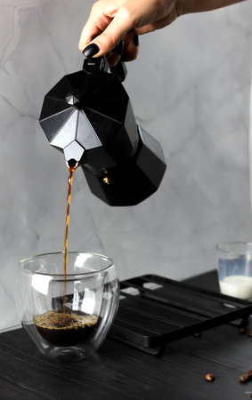 Pouring coffee into glass cup on table, closeup. Space for textの写真素材