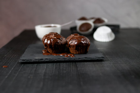 Chocolate muffins on a black plate on a dark background.の写真素材