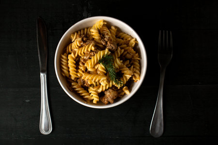 Pasta fusilli with meat in a bowl on black backgroundの写真素材