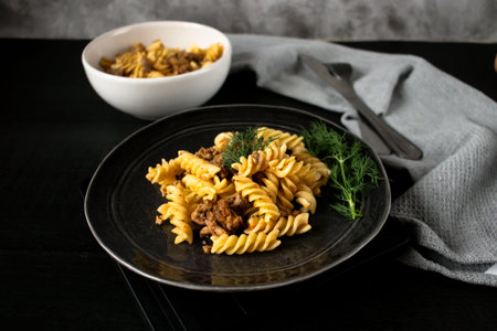 Pasta fusilli with meat and herbs on a black plateの写真素材