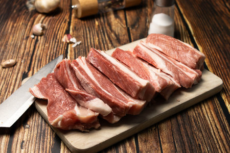 raw pork on cutting board with knife and garlic on wooden table backgroundの写真素材