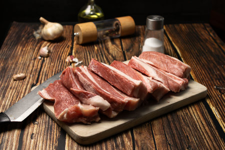 raw pork ribs on cutting board with salt and pepper on wooden tableの写真素材