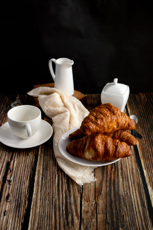 Breakfast with coffee and croissants on a wooden table.の写真素材
