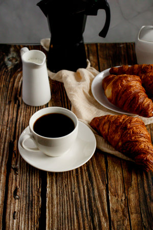 Breakfast with coffee and croissants on a wooden background.の写真素材